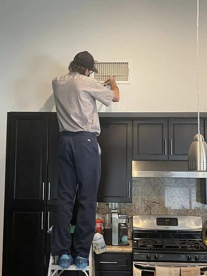 Technician inspecting an air vent during HVAC service in Tallahassee